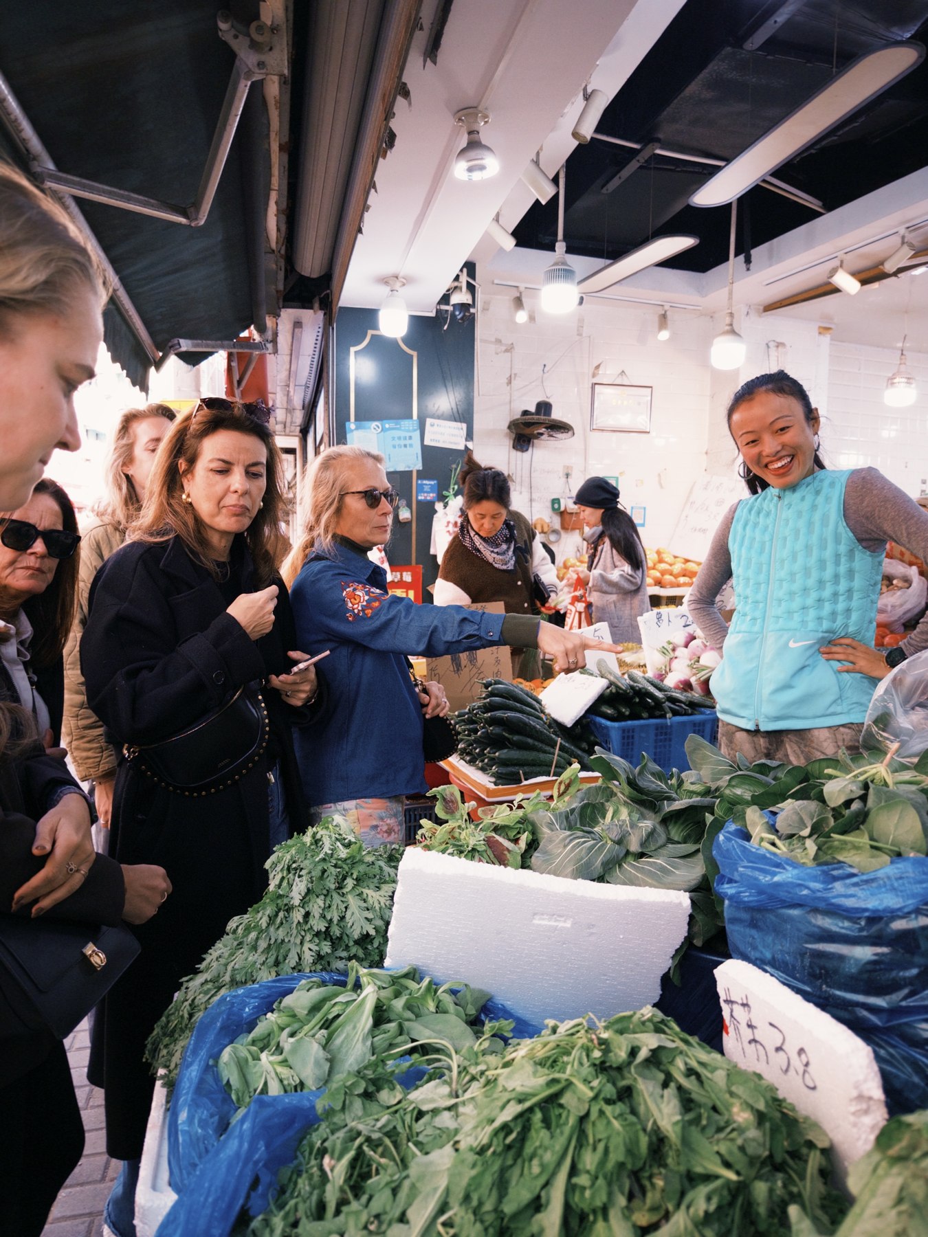 Guests exploring fresh vegetables with their host at a Shanghai market