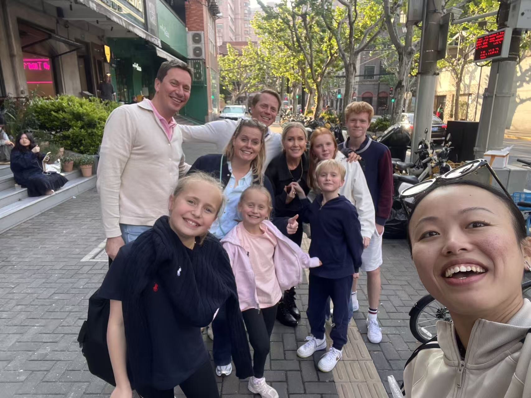 Guests and their host smiling together on a leafy Shanghai street
